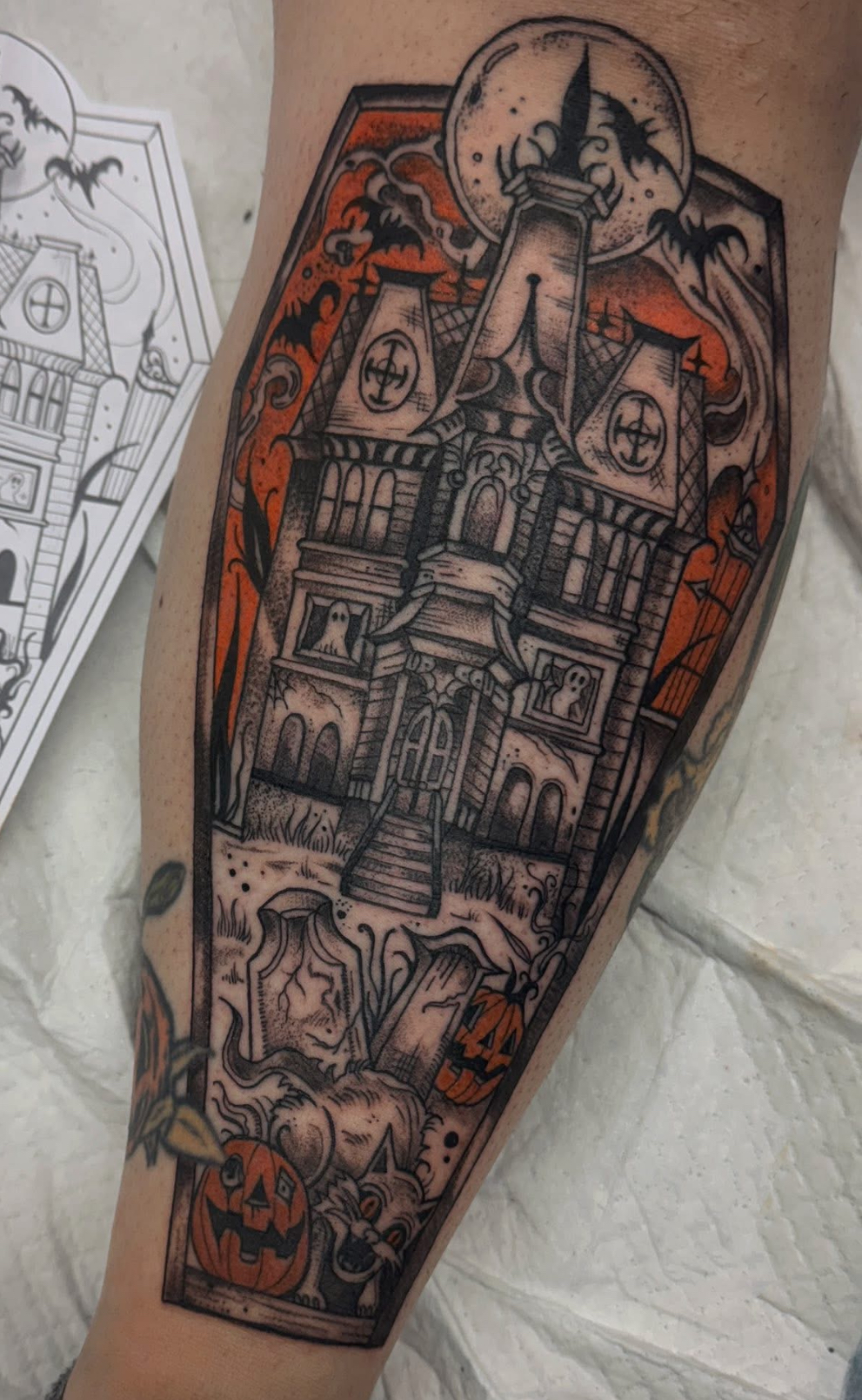Haunted cottage framed in a coffin with an orange sky, bats and jack-o'-lanterns