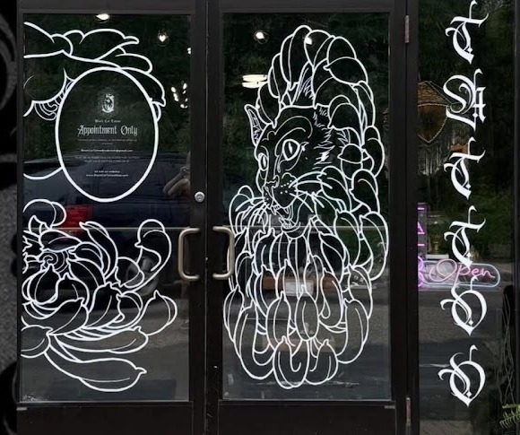 Black Cat Tattoo studio doors with cat and floral decals on Main Street in River Falls