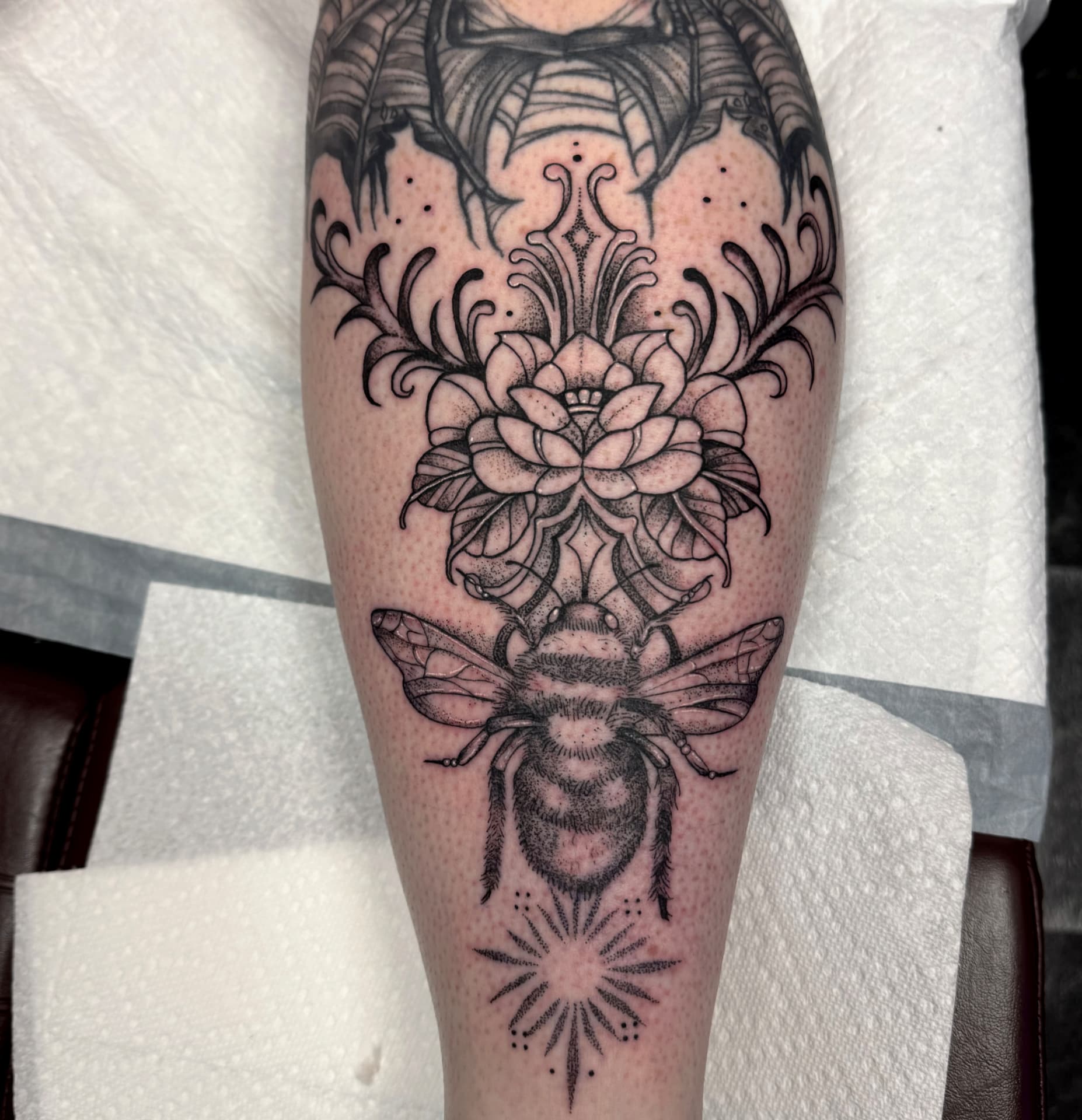 Dotwork bee and lotus ornamental calf tattoo with filigree flourishes