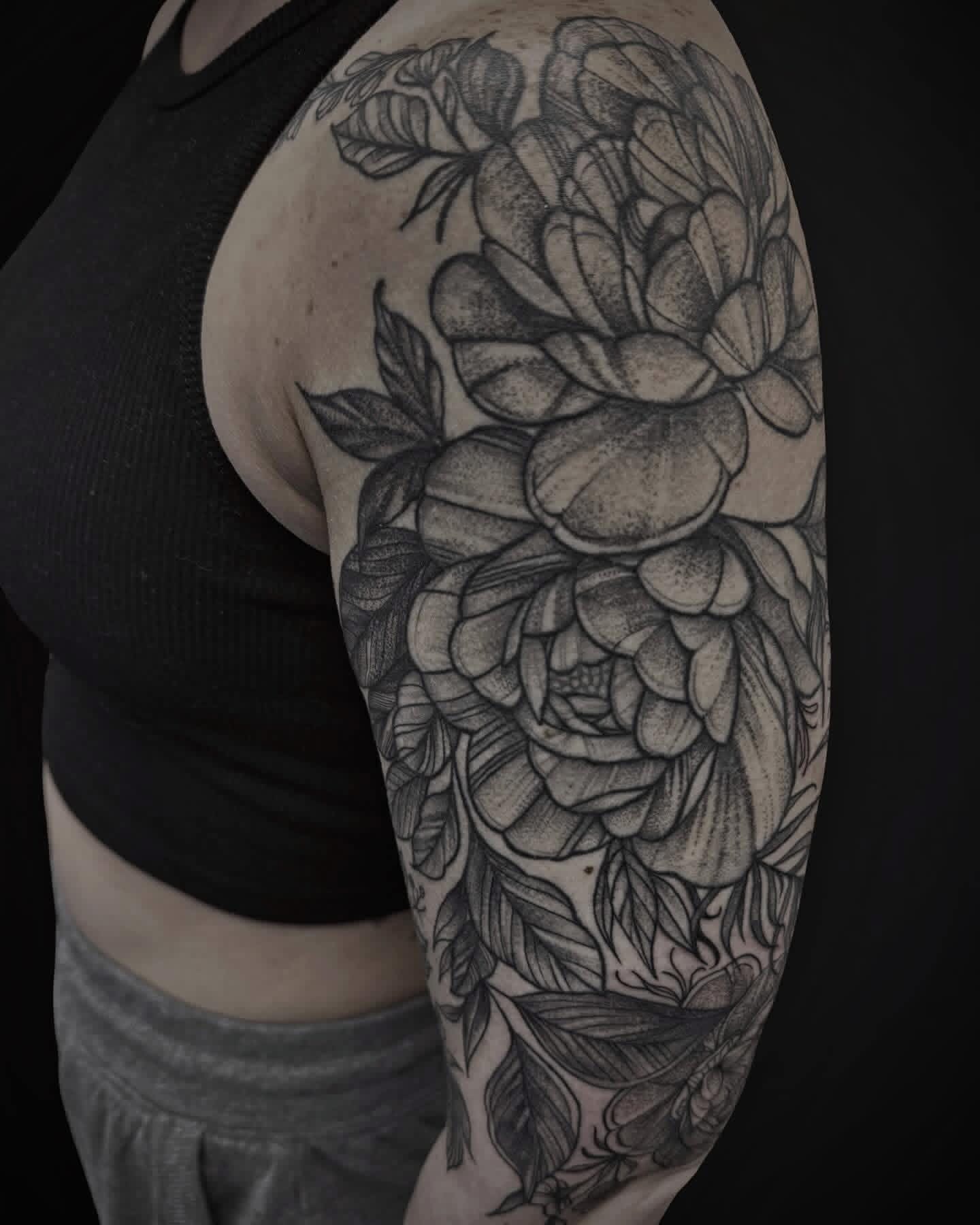 Dotwork peony half sleeve in black and grey with botanical leaves